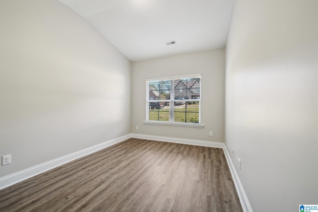 spare room with wood-type flooring and lofted ceiling