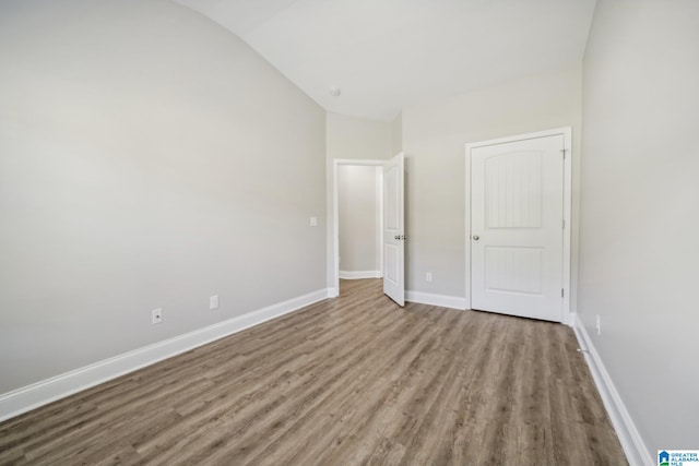 unfurnished bedroom with hardwood / wood-style flooring and lofted ceiling