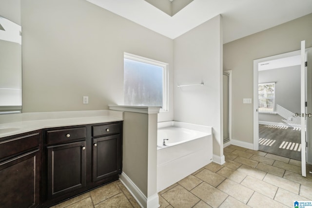 bathroom featuring plus walk in shower, vanity, and a healthy amount of sunlight