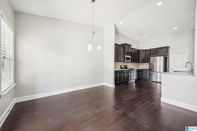 kitchen featuring sink, hanging light fixtures, stainless steel appliances, dark hardwood / wood-style floors, and dark brown cabinets