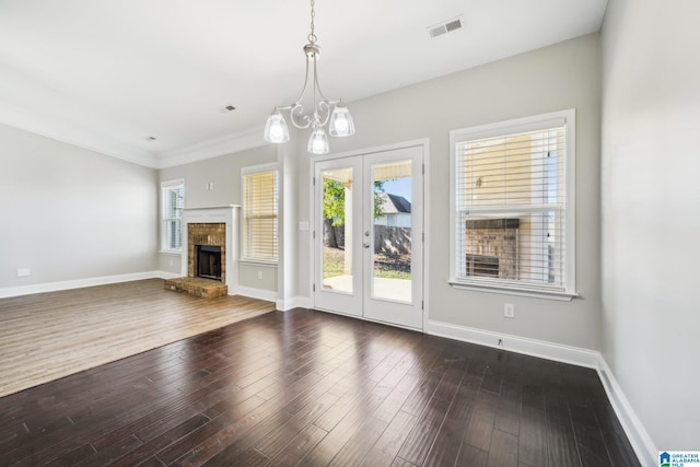 unfurnished living room with a fireplace, dark hardwood / wood-style flooring, a chandelier, and ornamental molding