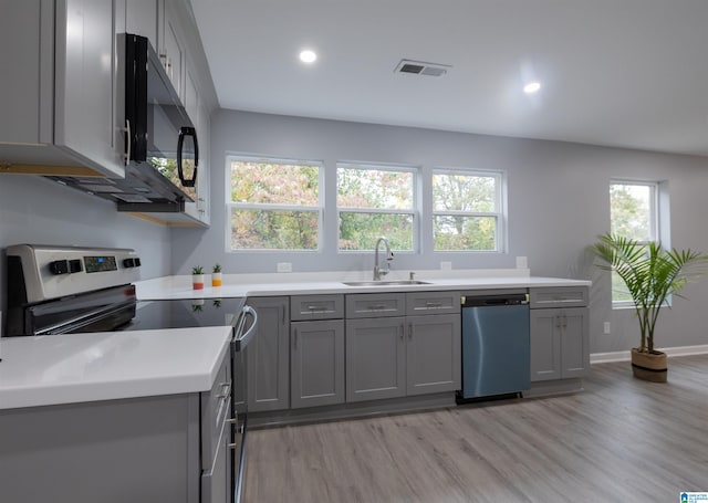 kitchen featuring stainless steel appliances, gray cabinets, light hardwood / wood-style floors, and sink