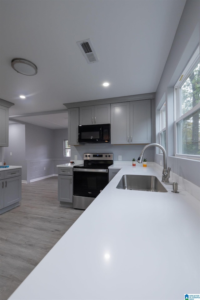 kitchen featuring sink, gray cabinets, light hardwood / wood-style flooring, and stainless steel electric range