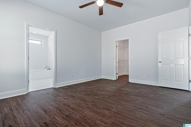 unfurnished bedroom featuring ensuite bath, ceiling fan, dark hardwood / wood-style floors, a walk in closet, and a closet