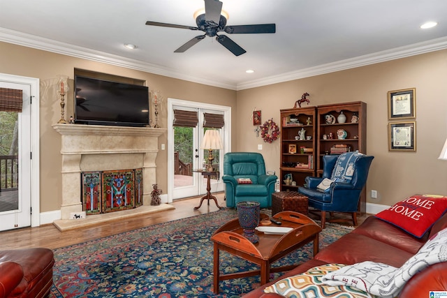 living room featuring hardwood / wood-style flooring, ceiling fan, ornamental molding, and a premium fireplace