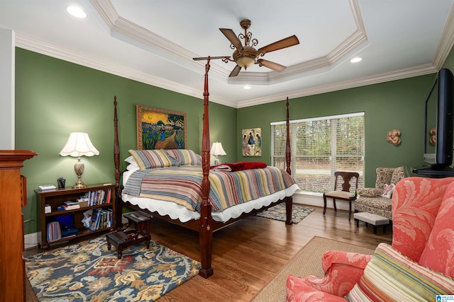 bedroom featuring hardwood / wood-style flooring, ceiling fan, a raised ceiling, and ornamental molding