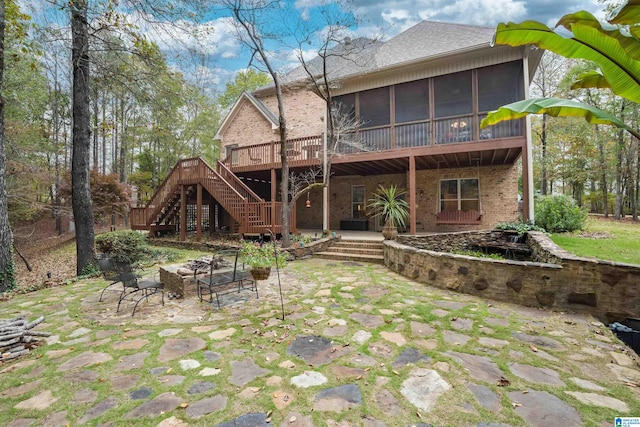 rear view of property with a patio, a wooden deck, and a sunroom