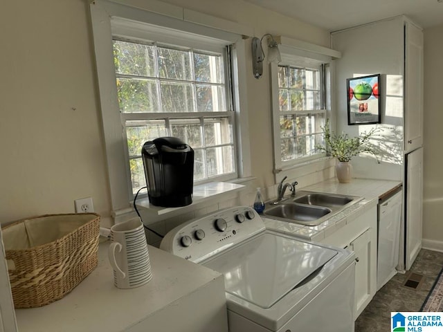 laundry room with washing machine and dryer, sink, and cabinets