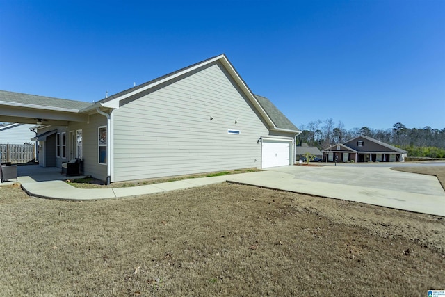 view of side of property with an attached garage, concrete driveway, and a yard