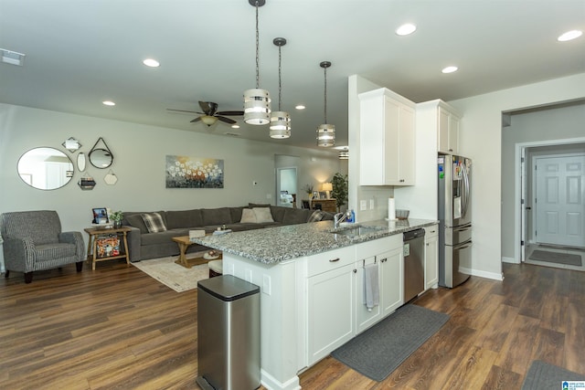 kitchen with open floor plan, stainless steel appliances, stone countertops, and white cabinets