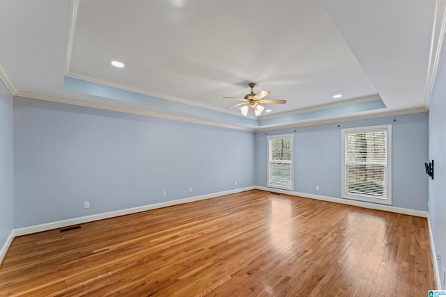 unfurnished room with ceiling fan, a raised ceiling, wood-type flooring, and crown molding