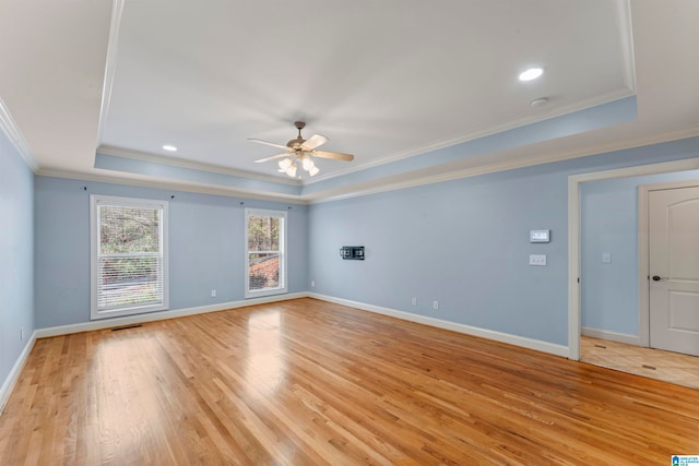 unfurnished room with a raised ceiling, ceiling fan, light hardwood / wood-style flooring, and ornamental molding