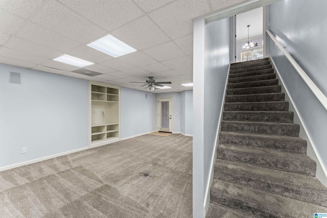 stairs featuring carpet flooring, a paneled ceiling, and ceiling fan with notable chandelier