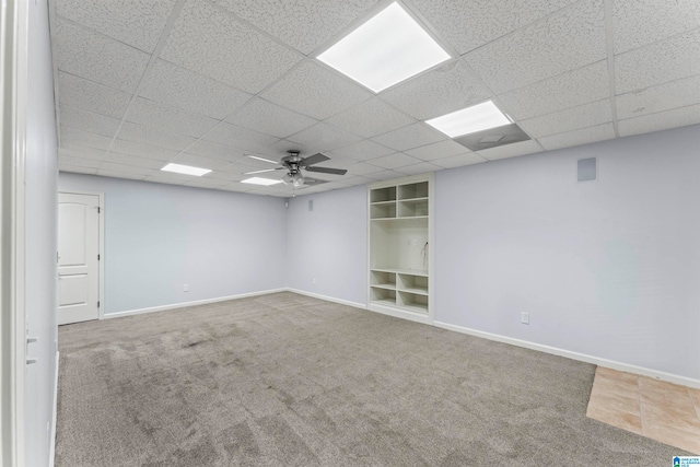 carpeted spare room with ceiling fan and a drop ceiling