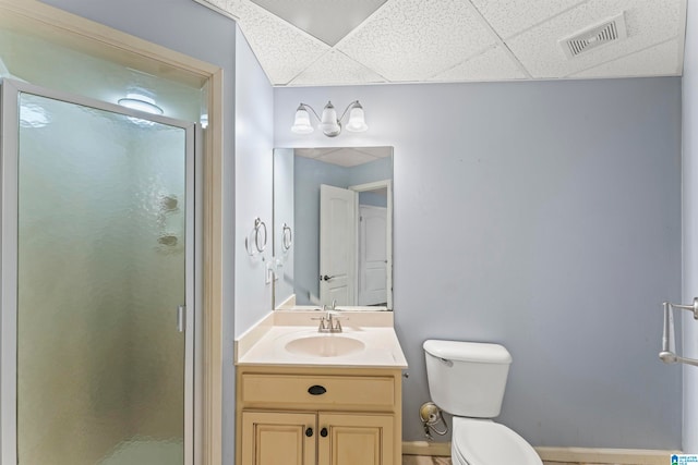 bathroom with a paneled ceiling, vanity, toilet, and walk in shower