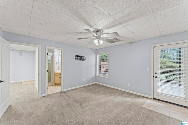 empty room featuring a drop ceiling, ceiling fan, and light carpet