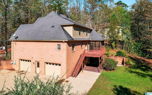 rear view of house with a sunroom, a garage, a deck, and a lawn