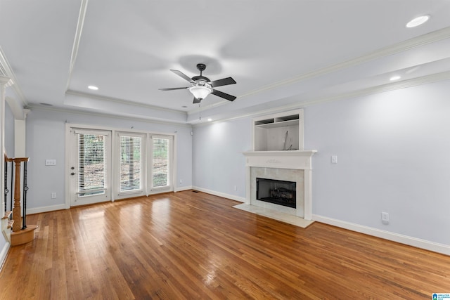 unfurnished living room featuring hardwood / wood-style floors, ceiling fan, a fireplace, and crown molding