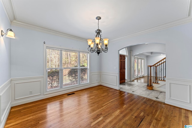 unfurnished dining area with a chandelier, light hardwood / wood-style flooring, and crown molding