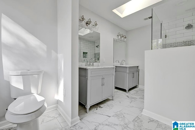 bathroom featuring a skylight, vanity, a shower with shower door, and toilet