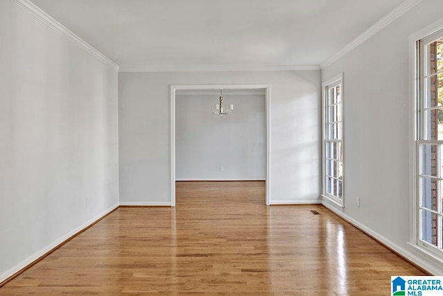 unfurnished room with an inviting chandelier, crown molding, and light hardwood / wood-style flooring