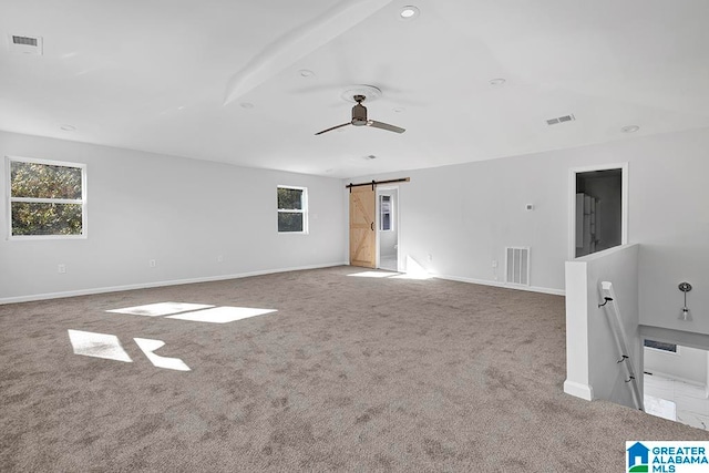 carpeted empty room with a barn door and ceiling fan