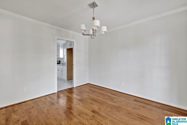 spare room featuring ornamental molding, light hardwood / wood-style floors, and a notable chandelier