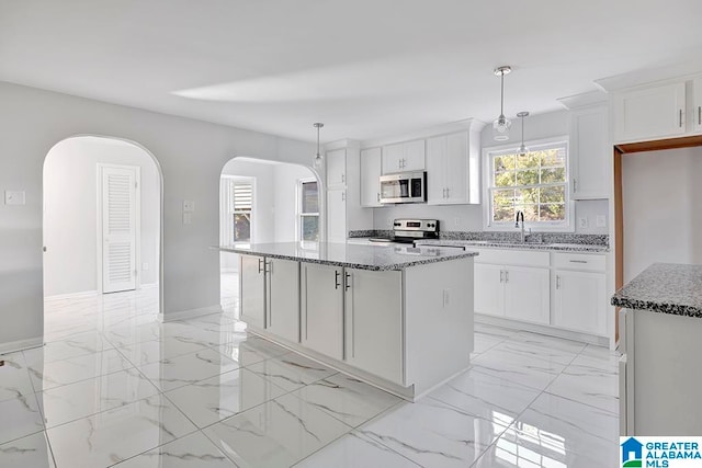 kitchen featuring appliances with stainless steel finishes, white cabinetry, a kitchen island, and pendant lighting