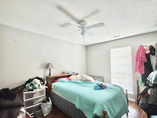 bedroom featuring ceiling fan, wood-type flooring, and a textured ceiling