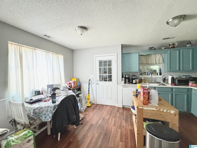 kitchen with dark wood-type flooring, white dishwasher, green cabinets, sink, and a textured ceiling