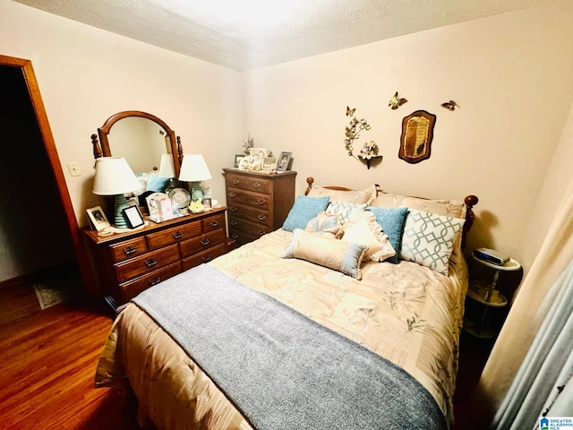 bedroom with dark hardwood / wood-style floors and a textured ceiling