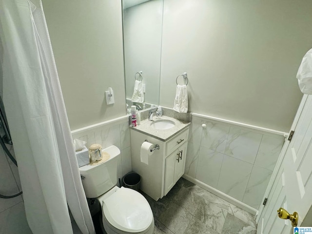 bathroom with vanity, toilet, and tile walls