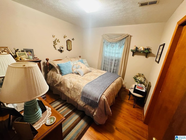 bedroom with wood-type flooring and a textured ceiling