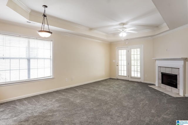 unfurnished living room featuring a tray ceiling, a fireplace, dark carpet, and ornamental molding