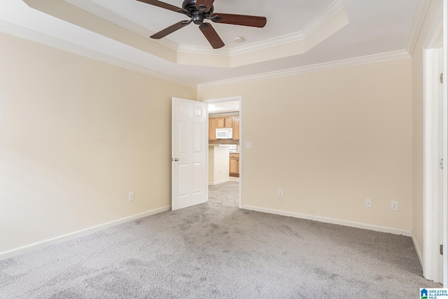 empty room with light colored carpet, crown molding, and a tray ceiling