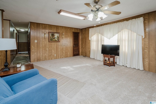 carpeted living room with ceiling fan and wooden walls