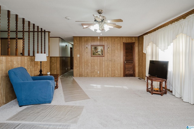 living room with carpet flooring, ceiling fan, and wooden walls