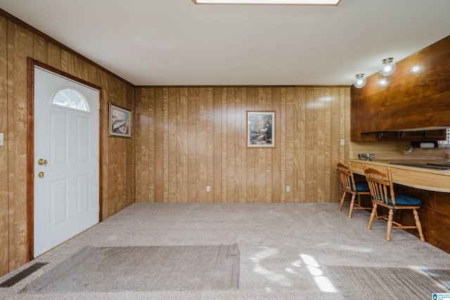 carpeted entryway with wooden walls