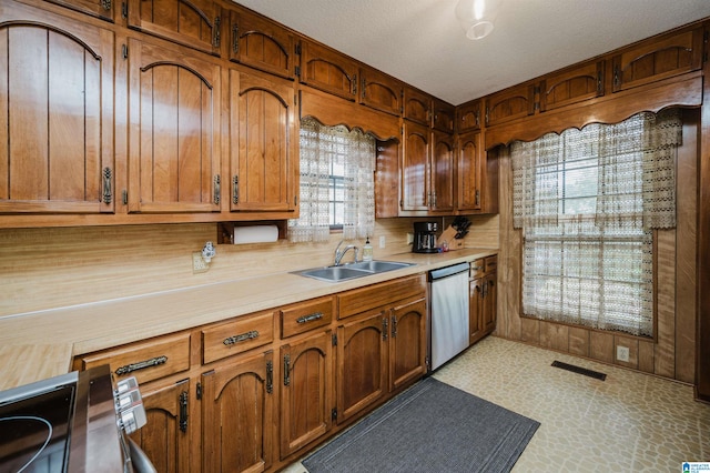 kitchen featuring stainless steel dishwasher, sink, and a textured ceiling