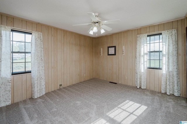 unfurnished room featuring ceiling fan, wooden walls, and carpet