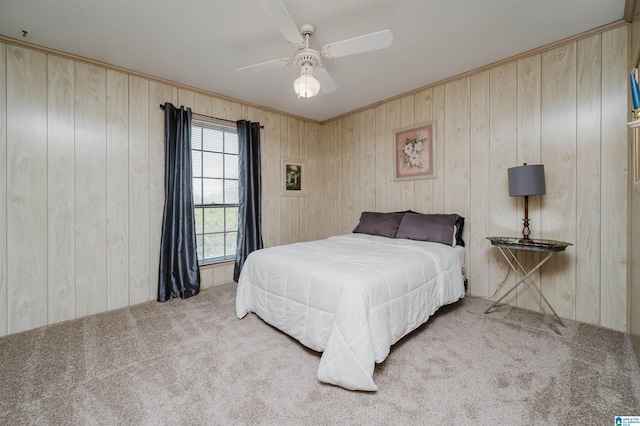 bedroom with carpet flooring, ceiling fan, and wooden walls