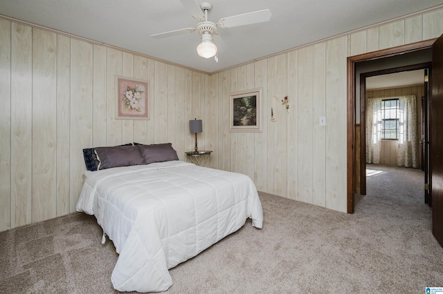 carpeted bedroom featuring ceiling fan and wood walls