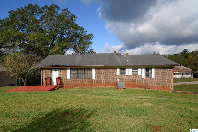 back of house with central AC unit and a yard