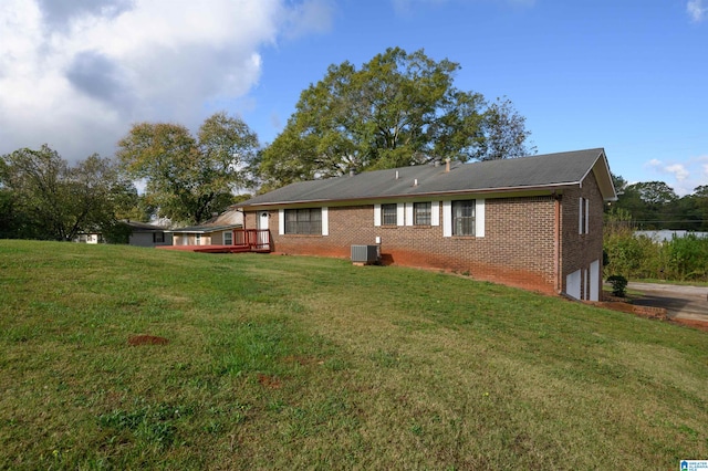 rear view of property with a garage, a yard, a deck, and central AC