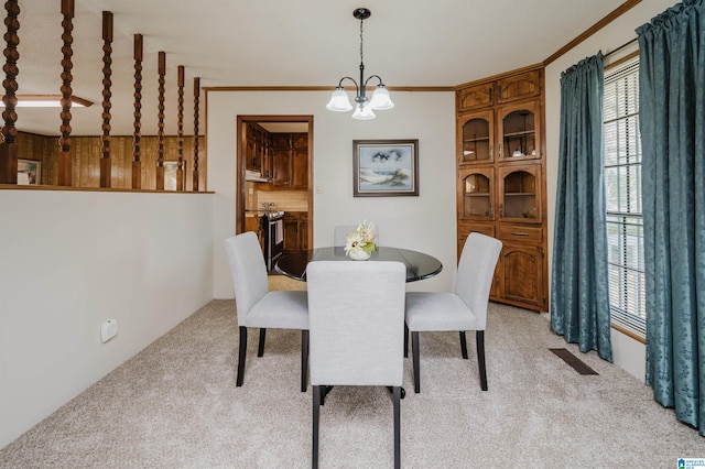 carpeted dining space with crown molding and a chandelier