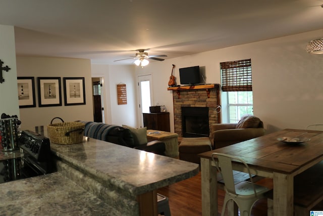 dining room featuring ceiling fan, a fireplace, and hardwood / wood-style flooring