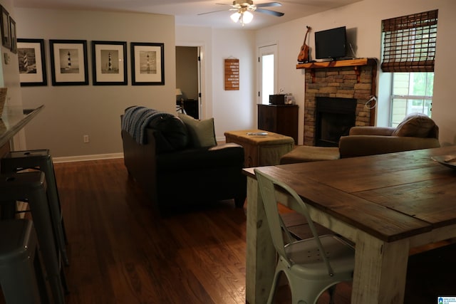 dining room featuring ceiling fan, a fireplace, and dark hardwood / wood-style floors