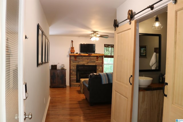 551 Poplar Pl, Wedowee, AL 36278 - living room with dark wood-style floors, ceiling fan, a barn door, a fireplace, and baseboards