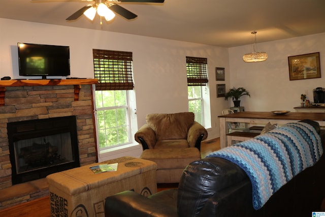 living room featuring hardwood / wood-style flooring, a stone fireplace, and ceiling fan