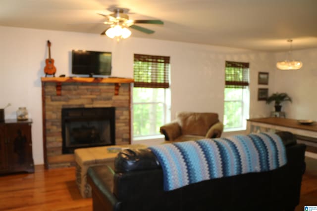 living room featuring a stone fireplace, ceiling fan, and hardwood / wood-style flooring